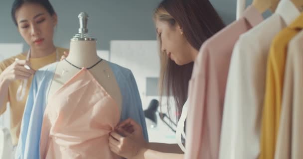Két profi ázsiai vidám hölgy divattervező csapatmunka alkalmi digitális tablet intézkedés szalag dummy hozzon létre ruha design a boltban. Női szabó üzlettárs induló vállalkozással. - Felvétel, videó