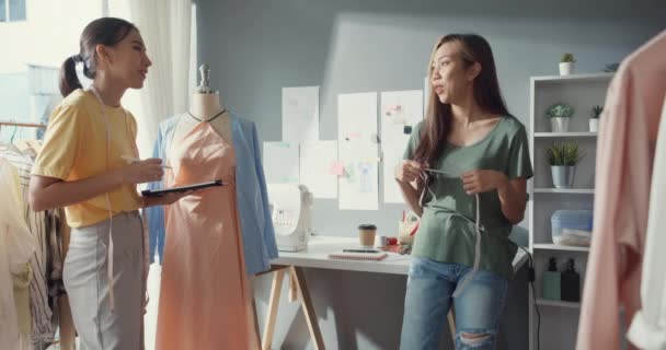 Dvě profesionální Asie veselá dáma módní návrhář týmová práce s ležérní s digitálním tabletu opatření páska na figuríny vytvořit šaty design v obchodě. Dámský krejčí obchodní partner se zahájením podnikání. - Záběry, video