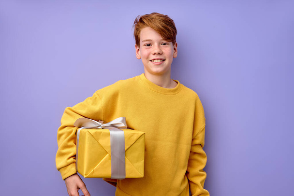 Excited happy pleased little boy holding gift box in hands, child enjoying birthday - Fotó, kép