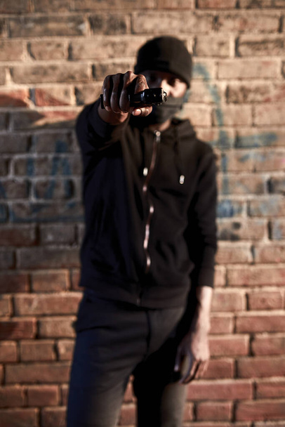 armed man rob people by gun on street, portrait of dangerous guy pointing gun at camera - Foto, Bild