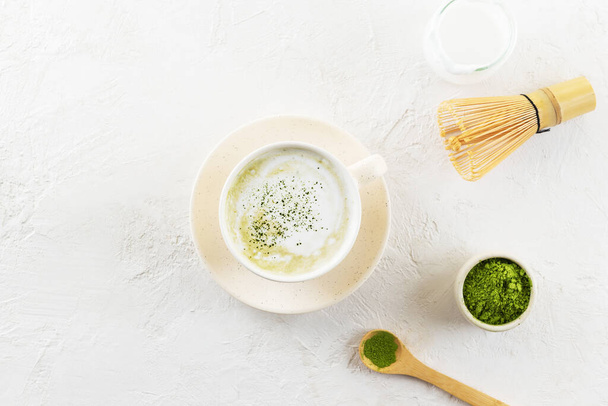 Matcha tea with coconut milk and a whisk in a light mug. Horizontal orientation, top view. - Fotografie, Obrázek