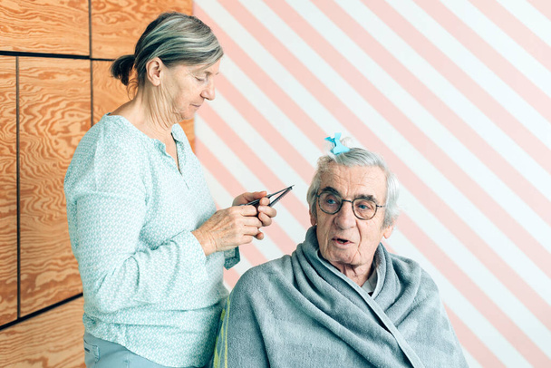 femme se préparant à couper les cheveux de son mari - couple âgé à la maison dans une journée normale de la vie - Photo, image