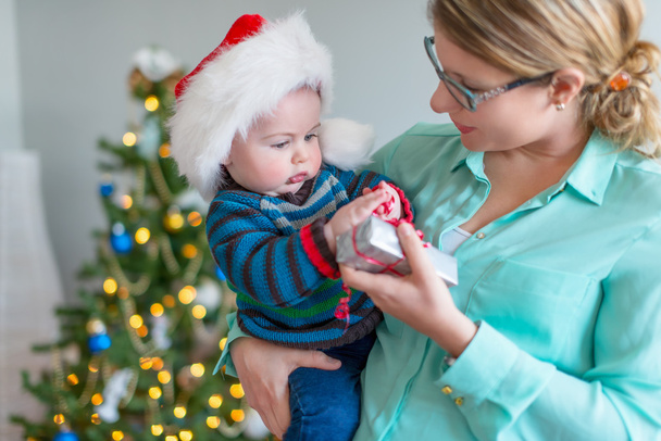 Niedliches Baby öffnet ein Geschenk seiner Mutter - Foto, Bild