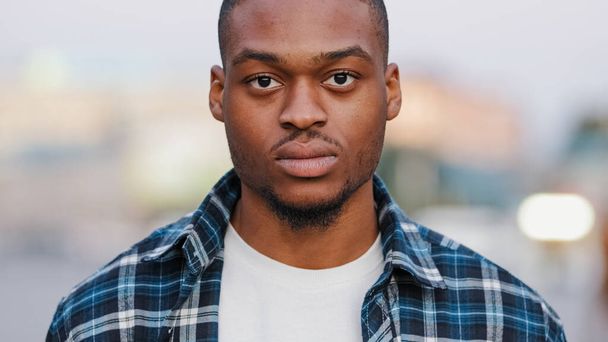 Portrait outdoors serious angry male face african american man looking at camera standing in urban city handsome confident guy looks street lifestyle. Real people close up facial confidence human gaze - Photo, Image