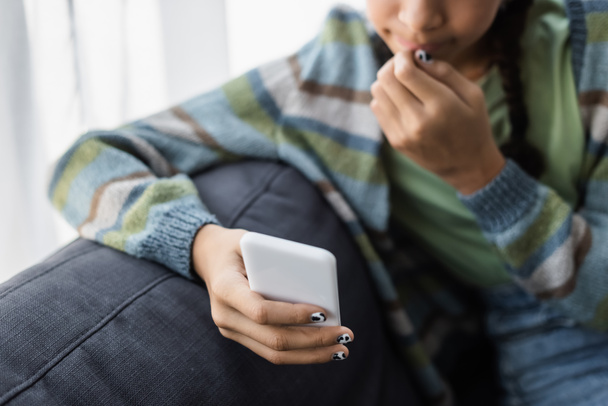 recortado vista de borrosa afroamericano adolescente chateando en el teléfono celular en casa - Foto, Imagen