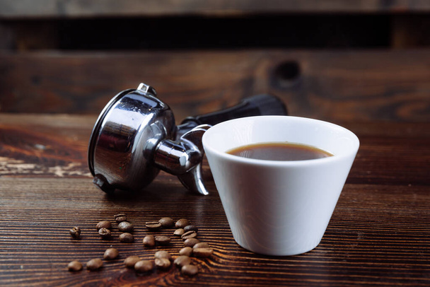 Een kopje zwarte koffie en filterhouder van espresso. - Foto, afbeelding