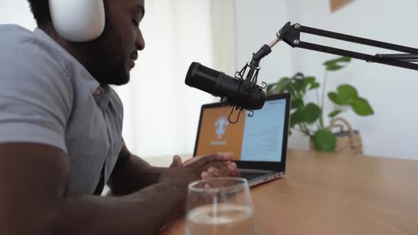 Afrikkalainen mies tallentaa podcast käyttäen mikrofonia ja kannettavaa kotoa studio - Materiaali, video