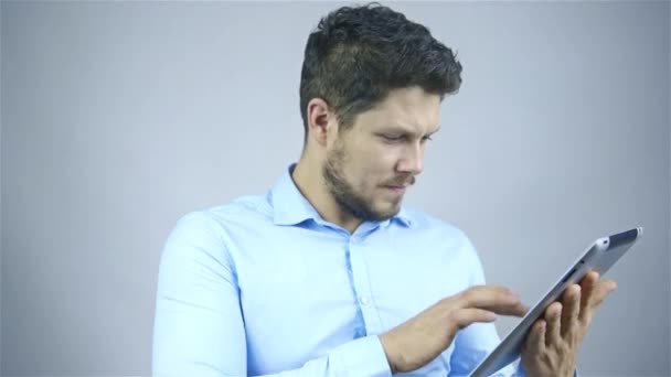 Businessman using a tablet computer - isolated over a grey background - Metraje, vídeo