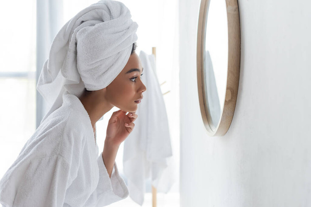 vista laterale di donna afro-americana guardando specchio in bagno - Foto, immagini