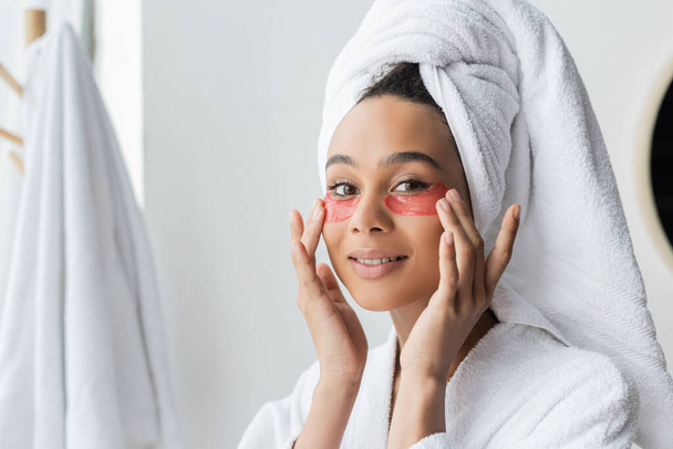 glückliche Afroamerikanerin trägt Augenklappen im Badezimmer auf  - Foto, Bild