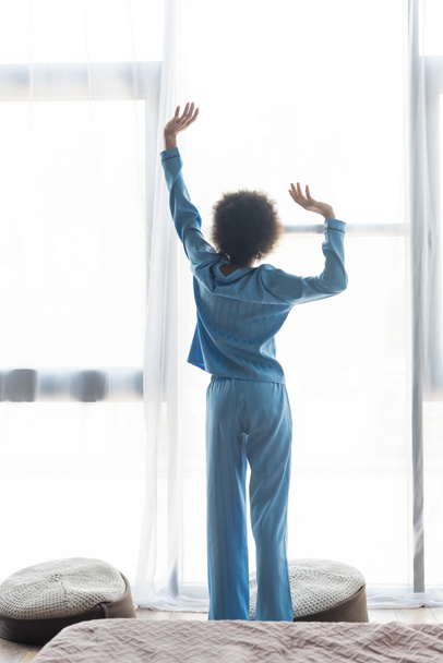 Back view of african american woman stretching in bedroom  - Photo, image