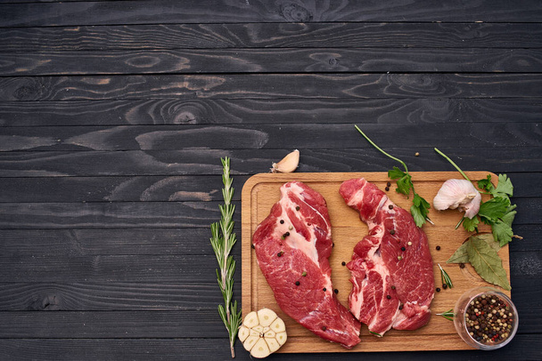 vlees steak houten plank en kruiden ingrediënten bovenaanzicht - Foto, afbeelding