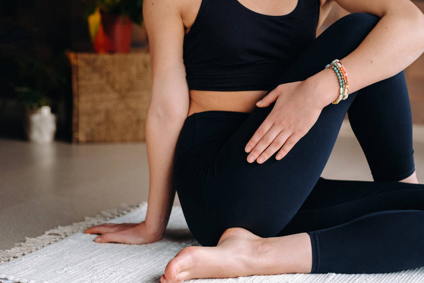 Close-up de uma jovem mulher de roupas pretas fazendo ioga em uma academia moderna.O conceito de saúde. - Foto, Imagem