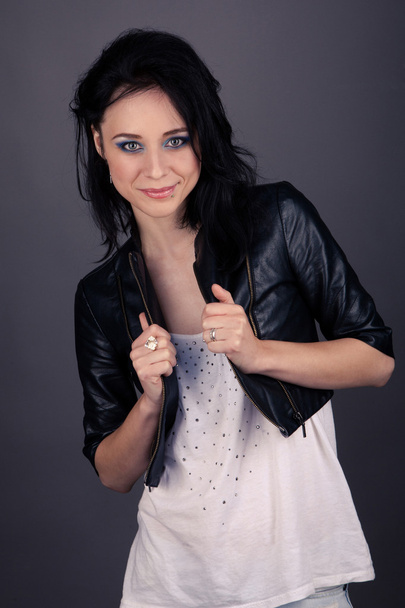 Pretty girl in leather jacket with piercings on a gray background - Foto, Imagen