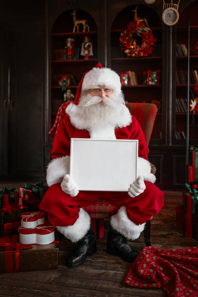 Weihnachtsmann mit weißem Rahmen in der Hand - Foto, Bild
