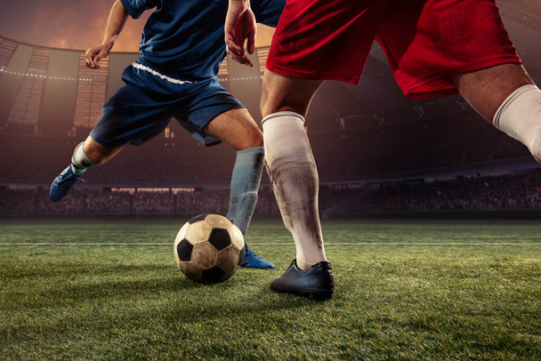 Two male soccer, football players dribbling ball at the stadium during sport match at crowed stadium. Sport concept - Photo, image
