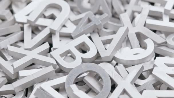 full frame close-up looped slowly rotating background of silver metal letters with selective focus - Footage, Video