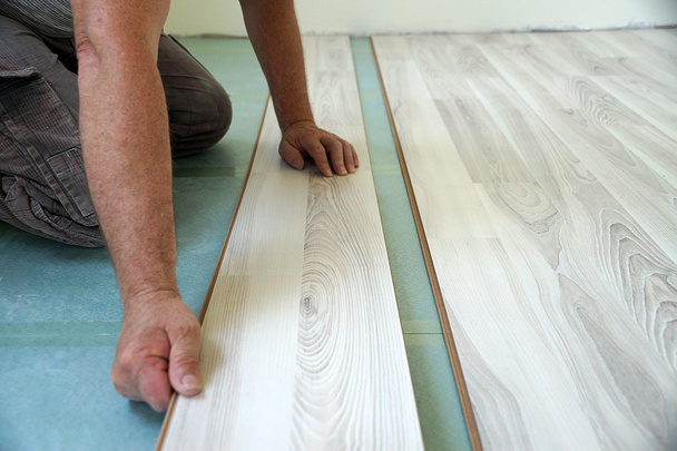 un trabajador monta un piso laminado en un primer plano de la sala de estar - Foto, imagen