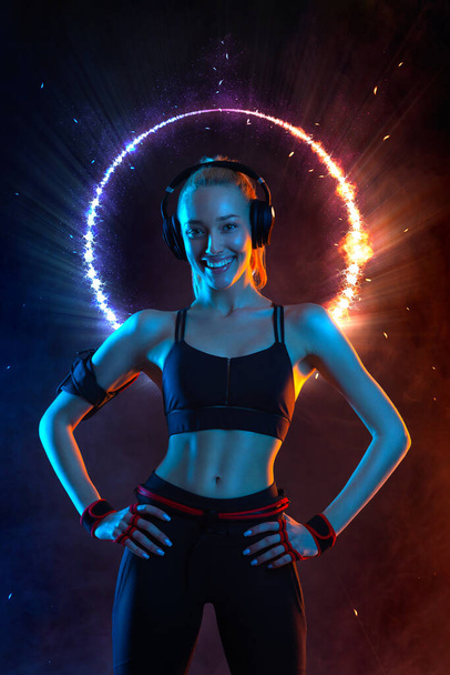 Strong athletic fit woman on black with neon lights background wearing in the sportswear. Fitness and sport motivation. - Fotó, kép