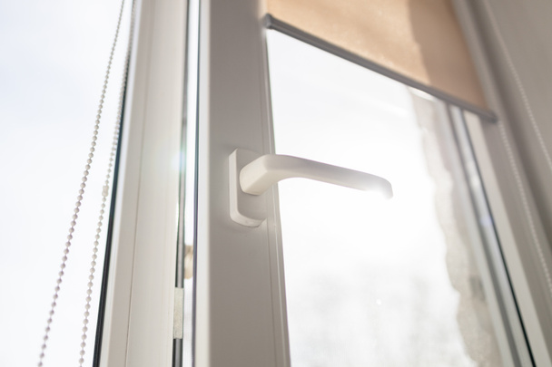Rollläden an den Fenstern, die Sonne dringt nicht ins Haus ein. Moderne weiße Kunststoff-PVC-Fenster mit Waldhintergrund zu Hause, Nahaufnahme. Innenraum - Foto, Bild
