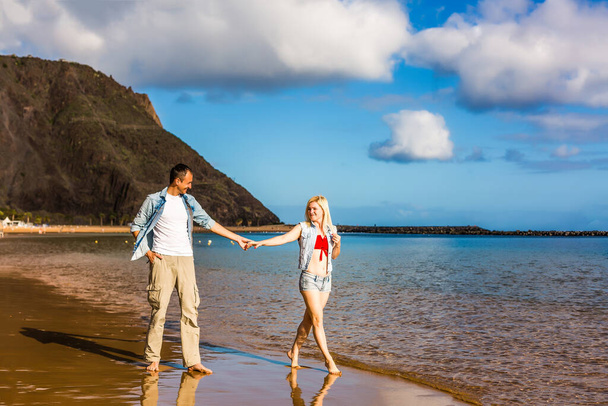 tropikal beyaz kum plaj boyunca yürüyen genç sevgili Çift - Fotoğraf, Görsel