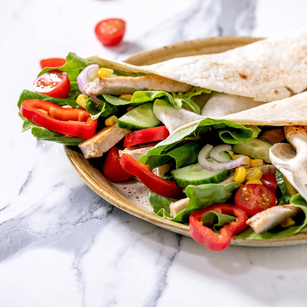 Traditional mexican tortila wrap with pork meat and vegetables in ceramic plate over white marble background. Close up. Homemade fast food. Square image - Fotografie, Obrázek