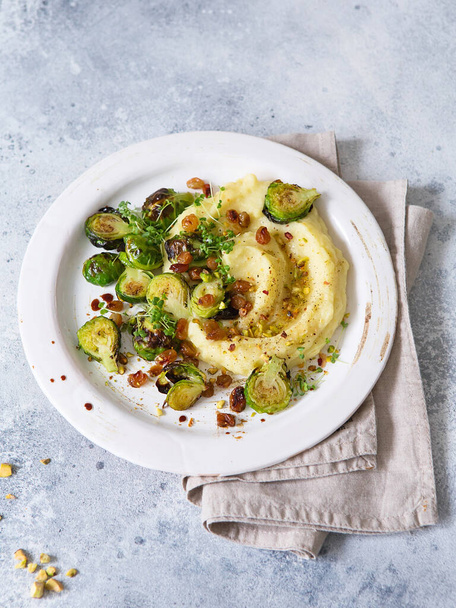 Brussels sprouts with pistachios, raisins and Skordalia (mashed potatoes). Healthy Meal preparation. Plant-based dishes. Green living. Vegan recipe. Food styling. Vegetarian cuisine. Healthy eating - Photo, Image