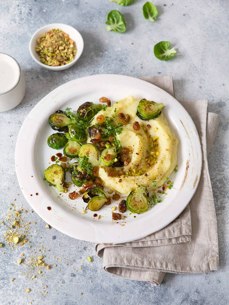 Brussels sprouts with pistachios, raisins and Skordalia (mashed potatoes). Healthy Meal preparation. Plant-based dishes. Green living. Vegan recipe. Food styling. Vegetarian cuisine - Photo, Image