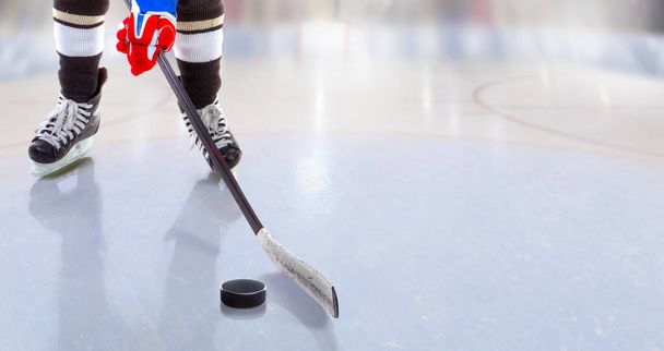 Tiefansicht eines Eishockeyspielers mit Stock auf der Eisbahn, der Puck und Kopierraum kontrolliert. - Foto, Bild