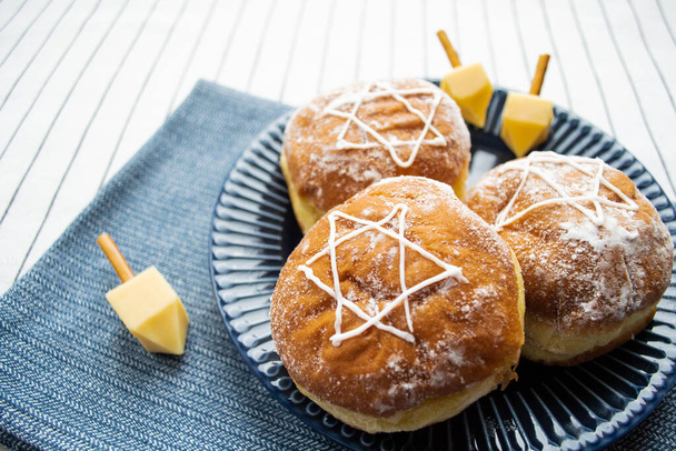 Feliz Hanukkah. Um doce tradicional de donuts com estrela David e dreidel feito de queijo e paus de biscoito. Espaço de cópia. - Foto, Imagem
