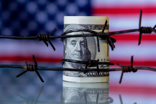 Koncepcionális kép: szögesdrót az amerikai dollárbankjegyekkel szemben, mint a gazdasági hadviselés szimbóluma, szankciók és embargó felszámolása.  - Fotó, kép