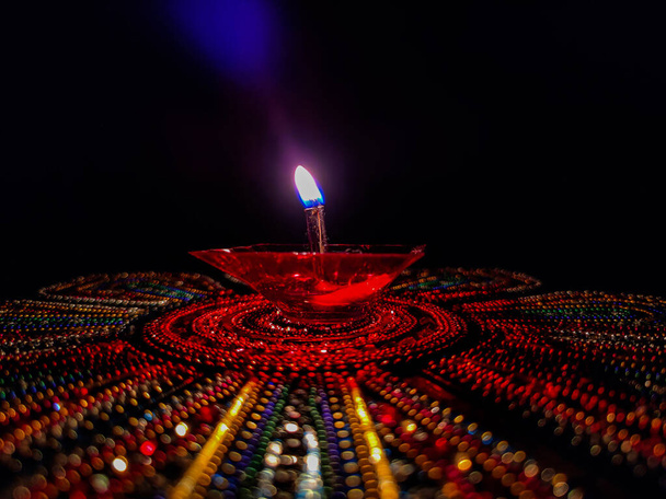 Фотографія чудових червонокольорових пластикових олійних ламп, освітлених особливо під час фестивалю дивалі, утримувалася на барвистих далечинах під темним фоном. Знімок виконано в Банглорі, Карнатака, Індія. фокусуйся на лампі - Фото, зображення