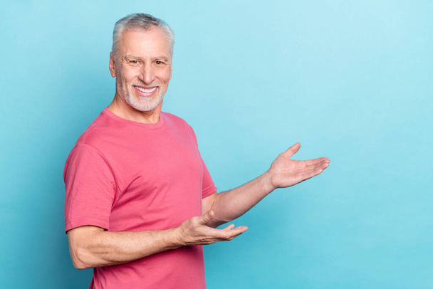 Photo portrait of bearded man pink t-shirt smiling demonstrating copyspace hands isolated pastel blue color background - Foto, Imagem