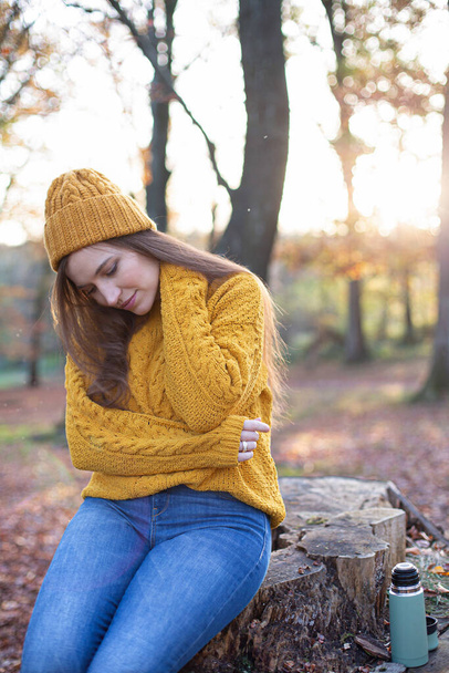 Young european white woman in yellow sweater feeling pain in her neck in sunny autumn forest - Foto, Imagen