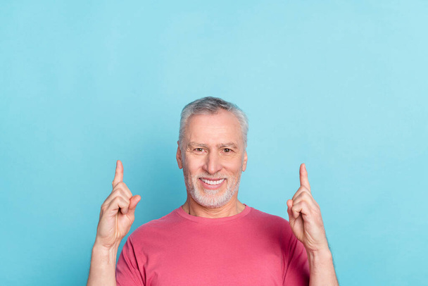 Portrait of attractive cheerful grey-haired man demonstrating up copy space ad decision isolated over bright blue color background - Фото, изображение