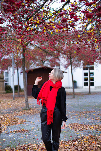 Walking european white young woman with blonde hair in red scarf in autumn - Photo, Image