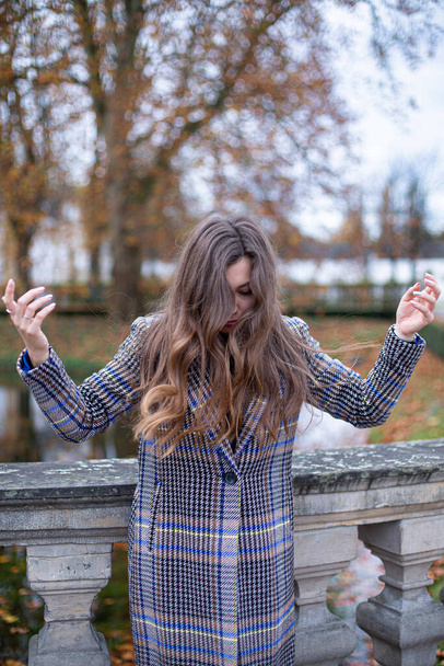 Young woman in trench coat with long curly hair in autumn park - Foto, immagini