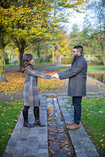 White young man and woman holding hands in autumn park - Fotoğraf, Görsel