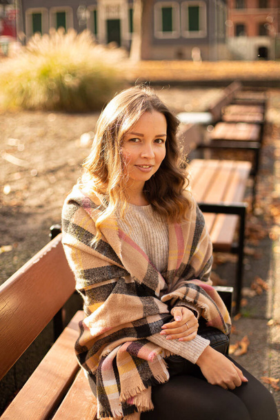 European white young woman with brown hair sitting on bench in sunny autumn - Φωτογραφία, εικόνα