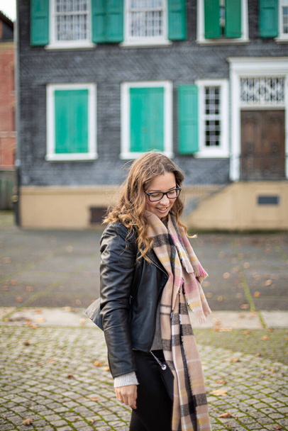 Smiling european young white woman with brown hair in glasses with building behind - 写真・画像