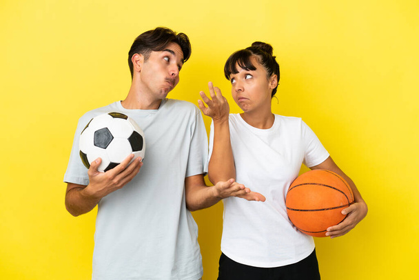 Futbol ve basketbol oynayan genç çift sarı arka planda izole edilmiş. Omuzlarını kaldırırken önemsiz bir jest yapıyorlar. - Fotoğraf, Görsel