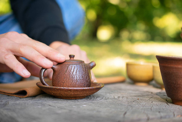 Handmade ceramic tea pot in closeup on stump in city park - Foto, immagini
