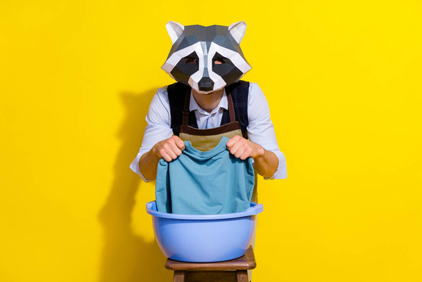 Photo of weird incognito unusual guy racoon mask wash clean dirt formalwear garment isolated over yellow color background - Foto, immagini