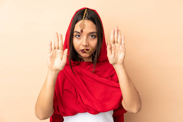 Young Indian woman isolated on beige background making stop gesture and disappointed - Photo, Image
