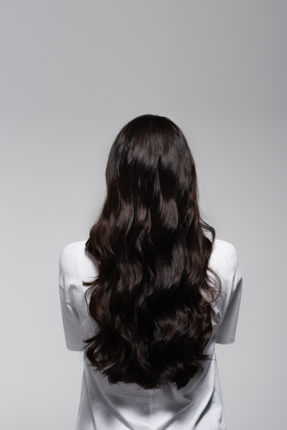 visão traseira da mulher morena com cabelos longos e brilhantes isolados em cinza - Foto, Imagem