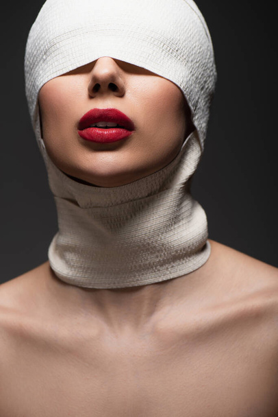 młoda kobieta w elastycznym bandażu z zakrytymi oczami i czerwonymi ustami wyizolowana na szaro - Zdjęcie, obraz