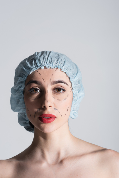csinos nő sebészeti sapka csupasz vállak és jelölt vonalak arcon elszigetelt szürke - Fotó, kép