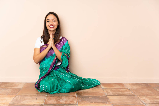 Yerde oturan genç Hintli kadın avuç içlerini bir arada tutuyor. İnsan bir şey ister. - Fotoğraf, Görsel