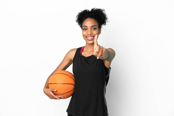 Jeune joueuse de basket-ball femme latine isolée sur fond blanc montrant et soulevant un doigt - Photo, image