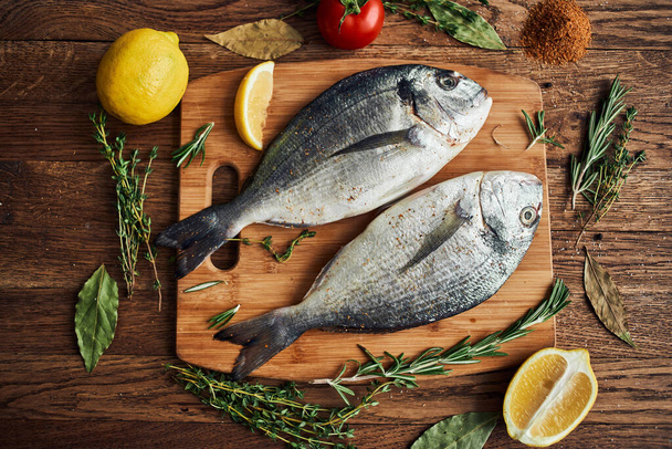pesce di mare ingredienti freschi limone su tavola di legno - Foto, immagini